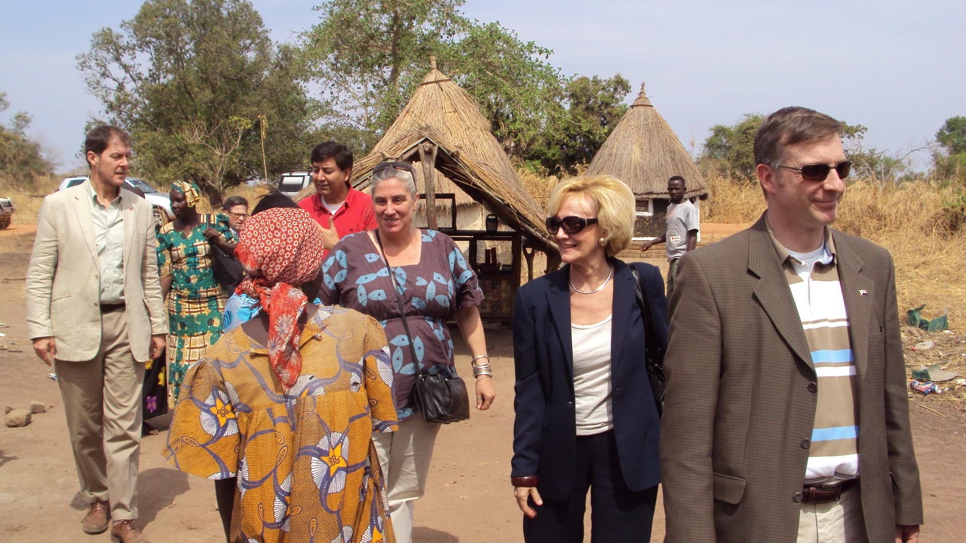 The delegation touring the community, with traditional homes in the background